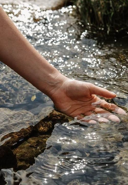 Mano rozando con suavidad el agua de un río